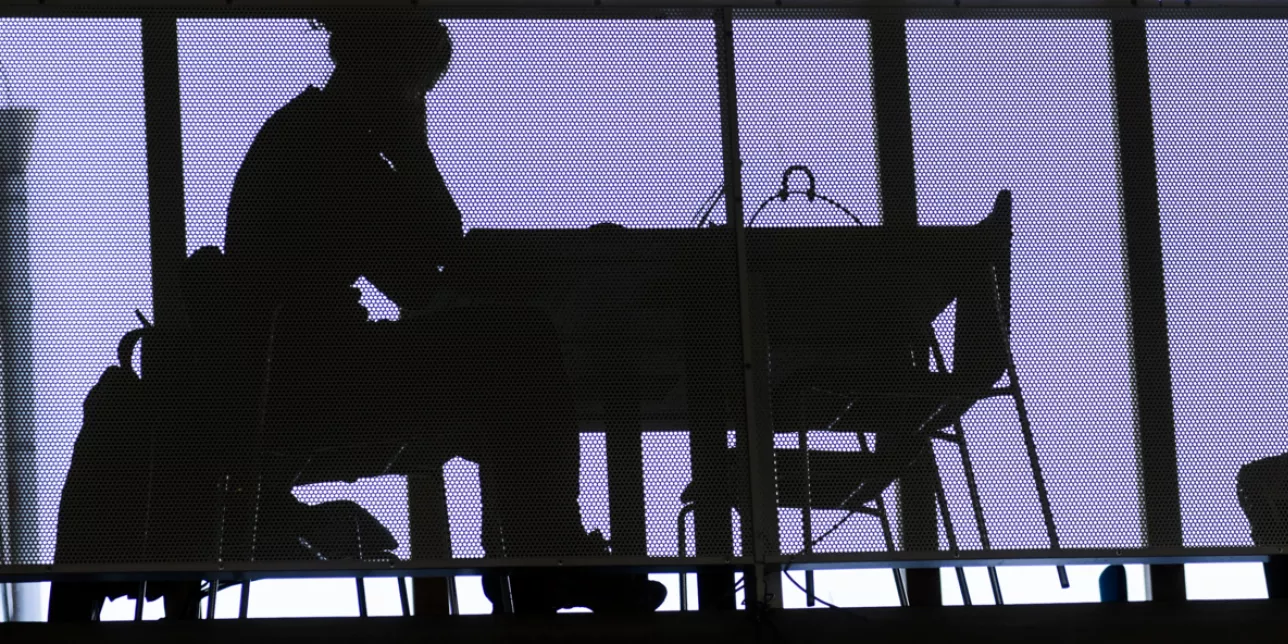 siluetter av två personer som sitter framför varsin dator. Foto: Kenneth Ruona.