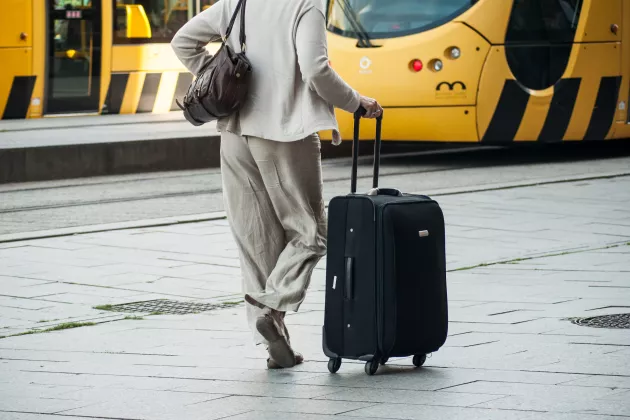 A woman with a suitcase in front of a train station.
