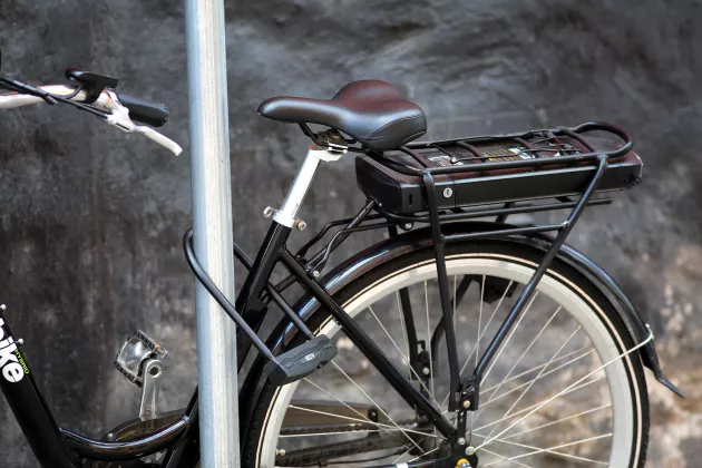 en elcykel som står parkerad mot en stolpe.