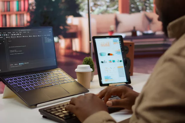 En man sitter framför en datorskärm och en Ipad.