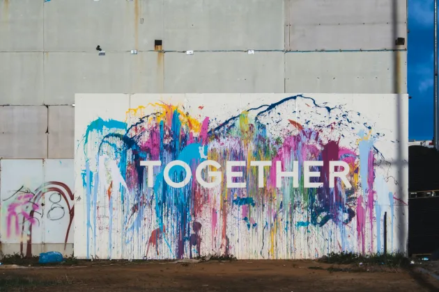 Together_nicole-baster-OJcEMZHoY80-unsplash.jpg Big wall splashed with colours and the letters forming "Together" in front.