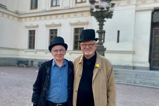 Göran Bexell och Martin Lind med doktorshattar framför universitetshuset.