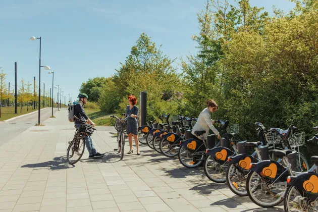 Några personer går för att hämta ut en lånecykel.