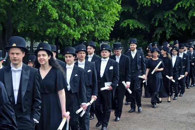 Ett stort antal människor i frack och svart långklänning går i procession.