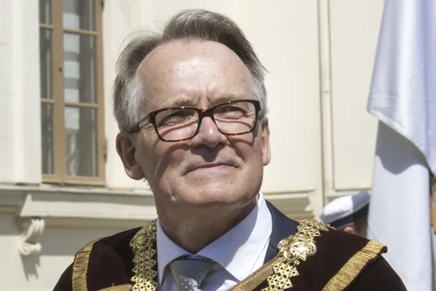 Porträttbild av man med glasögon, iklädd utstyrsel med gulddetaljer. 