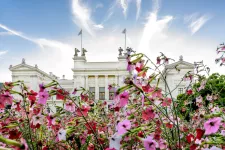 Universitetshuset med rosa blommor i förgrunden. Foto.