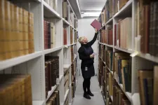 En bibliotekarie tar ner en bok från en hylla.