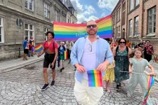 Jimmie Kristensson går främst i en LU-delen av Lundaprideparaden med en regnbågsflagga.