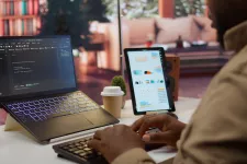 En man sitter framför en datorskärm och en Ipad.