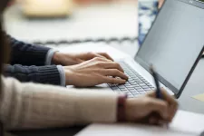 Två personers händer sitt och trycker på sina Laptops.