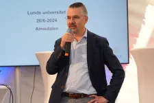 Erik Renström pratar med mikrofon på en scen.