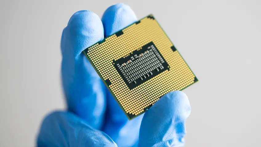 Hand som håller en liten metallisk platta. Foto.