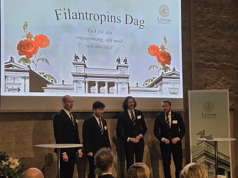 Fyra män i kostym står på en scen och sjunger.