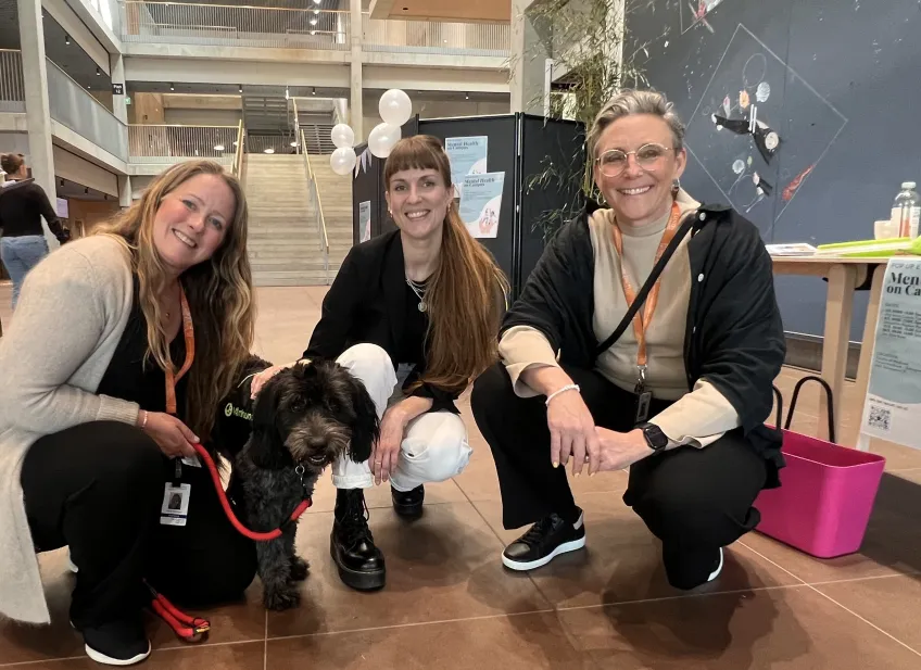 Tre kvinnor och en hund sitter på huk.