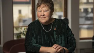 Foto på Ingrid Petersson sittande framför ett bord.