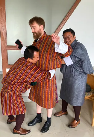 Två män klär på en tredje en dräkt. Foto.